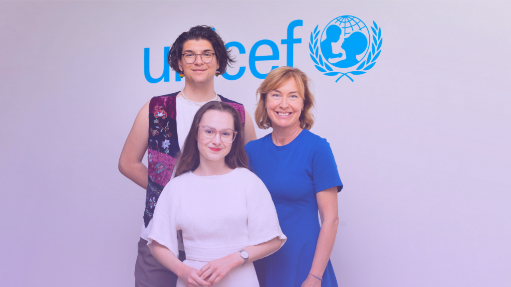 Foto på Elias Fjellander, Pernilla Baralt och Lilian Helgason framför en vit vägg med UNICEF:s logga i blått. Alla tittar in i kameran och ler.