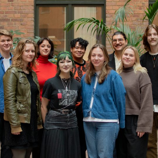 Gruppfoto på förbundsstyrelsen inomhus. Från vänster till höger står Eric, Flora, Kevin, Elias, Jakob, Frida, Max, Lina och Lydia. Alla ler in i kameran.