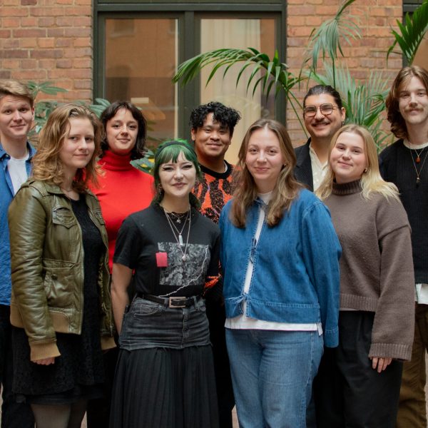 Gruppfoto på förbundsstyrelsen inomhus. Från vänster till höger står Eric, Flora, Kevin, Elias, Jakob, Frida, Max, Lina och Lydia. Alla ler in i kameran.