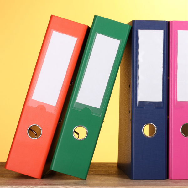 Foto på en orange, grön, mörkblå och rosa pärm mot en gul bakgrund.