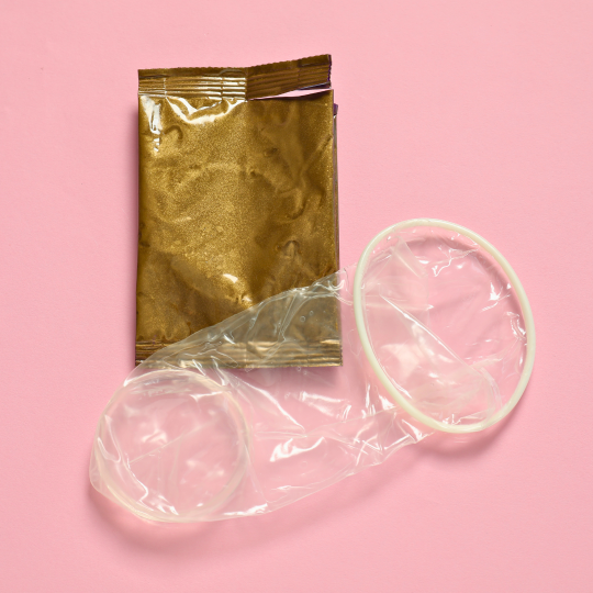 Närbild på en inidom och en omärkt förpackning i guldfärg mot en rosa bakgrund.