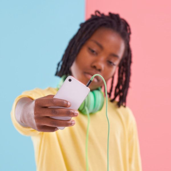 Foto på en person som håller upp en smartphone framför en ljusblå och ljusrosa bakgrund.